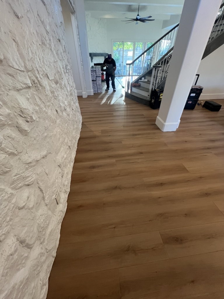 Apex Point Services crew installing LVP flooring next to stone accent wall in Rowlett TX home